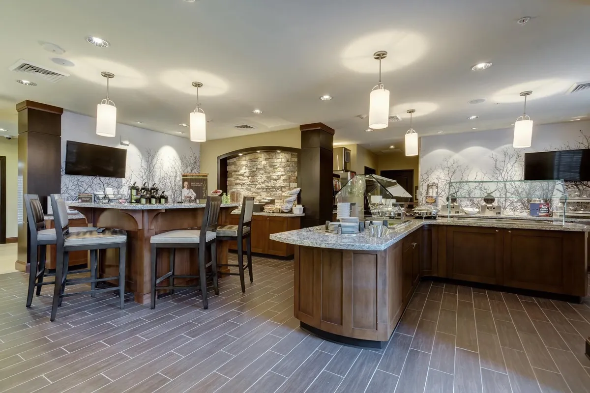 A cozy dining area with bar seating, a stone accent wall, and a buffet station. The inviting atmosphere is perfect for enjoying the hotel's complimentary breakfast or a casual meal with friends and family.