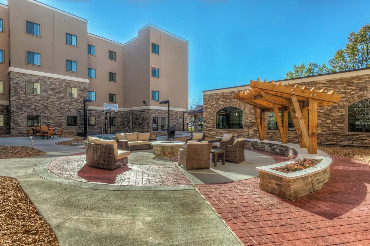 An outdoor seating area complete with a cozy fire pit, pergola, and a stone pathway creates a communal, family-friendly environment. The space is designed for relaxing, enjoying outdoor treats, or gathering after a day of exploration.